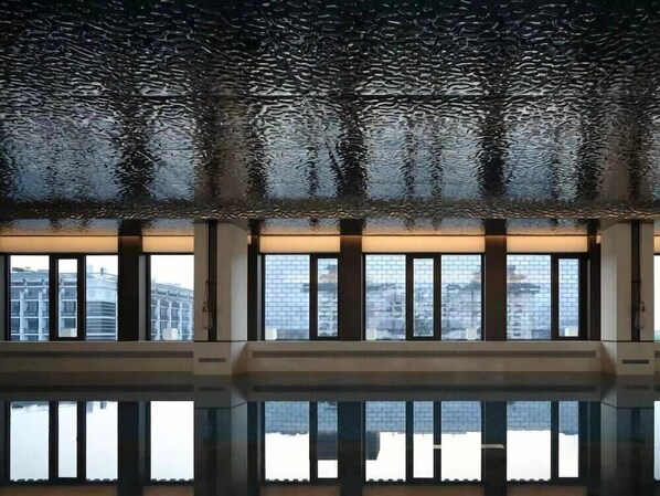 A modern interior with large windows, a reflective floor, and a patterned ceiling. - Prime (Beijing)