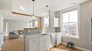 Een moderne keuken met een groot eiland, witte kasten en uitzicht op de stad.