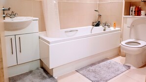 A modern bathroom with a bathtub, a toilet, a sink, and a shower. - 9 mins from the northern line station. 2 mins from 3 B/stops and local amenities (London)