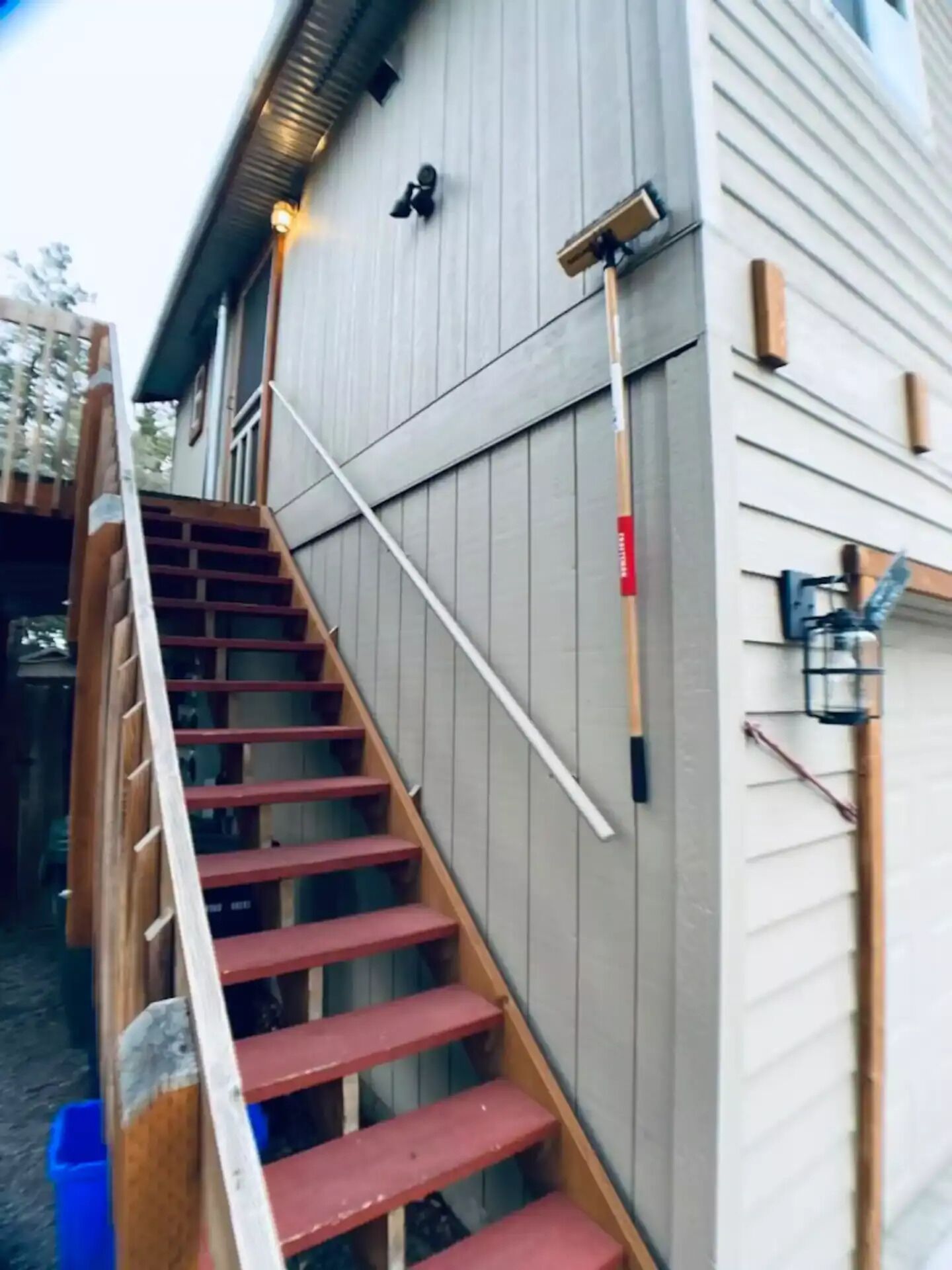 Een houten trap die leidt naar een gebouw met een grijze gevel.