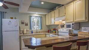 Una cocina con mostradores de madera, un refrigerador, un microondas y un lavamanos.