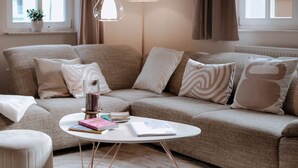 A cozy living room with a beige sofa, a white coffee table, and a floor lamp.
