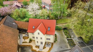 A two-story building with a red roof, a courtyard with a bench, and a small garden area.
