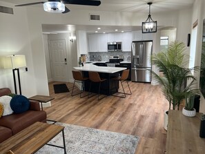 Relax in a spacious living area with a comfortable sofa and coffee table, and cook in a well-equipped kitchen with a large island and bar stools.
