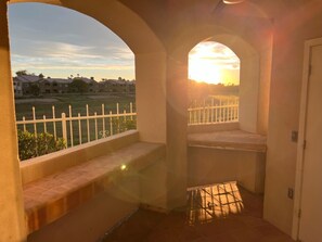 Enjoy a serene view of the surrounding neighborhood from this balcony with a seating area and curved archway.