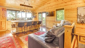 Interior de una cabaña de madera con cocina, comedor y sala de estar.
