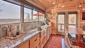 Una cocina moderna con armarios de madera, encimera de granito, pileta de acero inoxidable y un ventanal con vistas al exterior.
