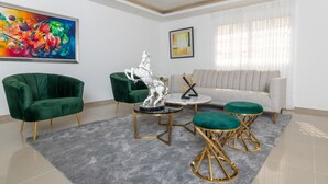 A modern living room with a green sofa, two green armchairs, a white sofa, and a coffee table with a silver statue. - Beautiful villa in Santo Domingo is  (Santo Domingo Este)