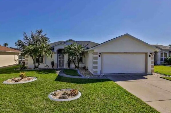 Stunning single-story home with a central entrance, flanked by palm trees, and a well-manicured lawn.