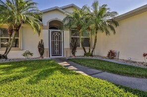 Stunning entrance with a beautifully manicured yard and elegant arched doorway.
