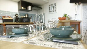 A dining table set with clear glassware and teal bowls, with a kitchen in the background.
