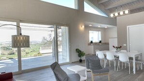 En modern inredning med ett matområde, en soffa och utsikt genom stora fönster.