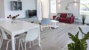 Ett modernt vardagsrum med ett vitt matbord, en röd soffa och en tv.
