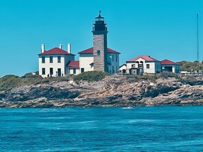 A coastal lighthouse with a tower and multiple buildings with red roofs.