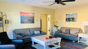 A living room with two sofas, a coffee table, a black chair, and a ceiling fan. - Close to Beach heated salt Pool Retreat (Naples)