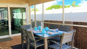 A dining area with a table set for four, chairs, a ceiling fan, and a view of greenery outside. - Close to Beach heated salt Pool Retreat (Naples)