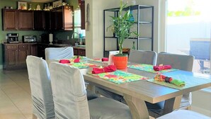 A dining area with a wooden table, four chairs, and a potted plant. - Close to Beach heated salt Pool Retreat (Naples)