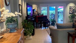 Ett rymligt vardagsrum med ett piano, en tv och ett stort fönster med utsikt över omgivningen.
