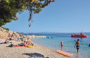 A beach with people sunbathing, swimming, and a lifeboat in the water. - 1 bedroom beautiful apartment in Podaca (Podaca)