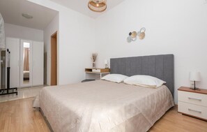 A bedroom with a bed, bedside tables, a desk, and a wardrobe. - 1 bedroom beautiful apartment in Podaca (Podaca)