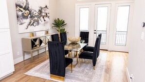 Un espace repas avec une table en verre, des chaises noires et un élément décoratif central.