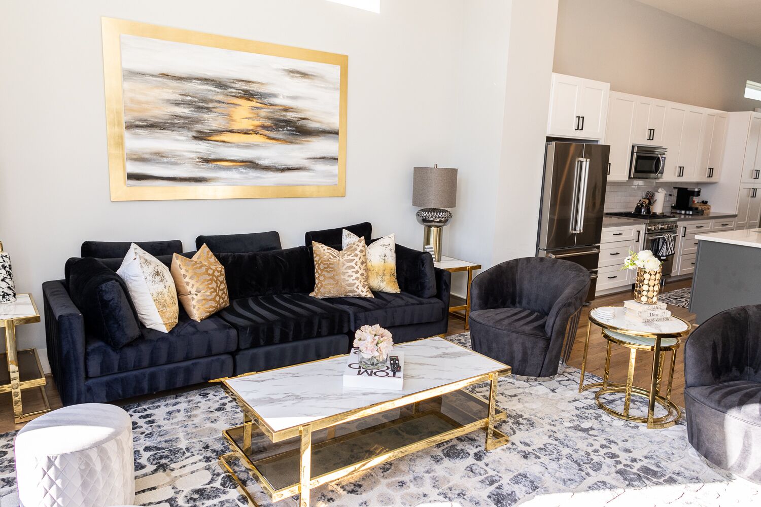 A modern living room with a dark blue sofa, gold accents, and a marble coffee table.