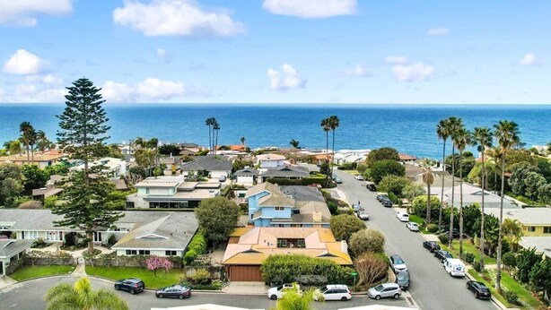 Una zona residenziale costiera con case, una strada e l'oceano sullo sfondo.