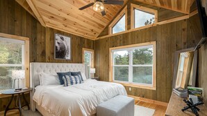 Una camera da letto con un letto grande, una ventola a soffitto e diverse finestre.