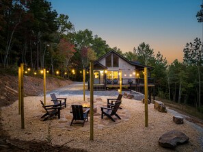 Una cabaña con patio de piedra, mobiliario exterior e iluminación colgante.