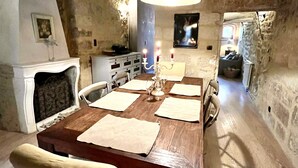 A rustic dining area with a wooden table, chairs, and a hanging light fixture. - Beautiful Townhome in Uzès Center (Uzès)