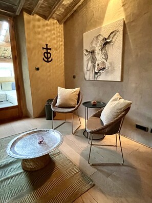 A cozy room with a round table, two wicker chairs, a small round table, and a wall-mounted artwork of a cow. - Beautiful Townhome in Uzès Center (Uzès)