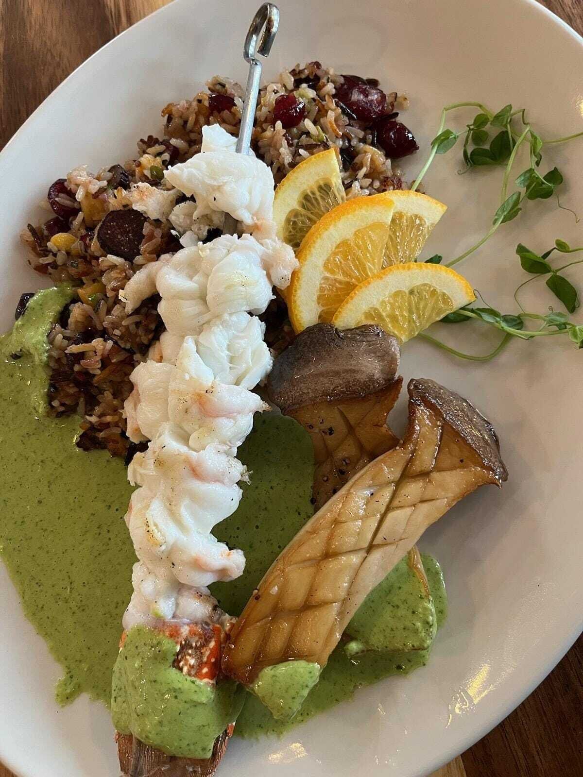 Une assiette de nourriture composée de riz, de crevettes et d’une sauce verte.