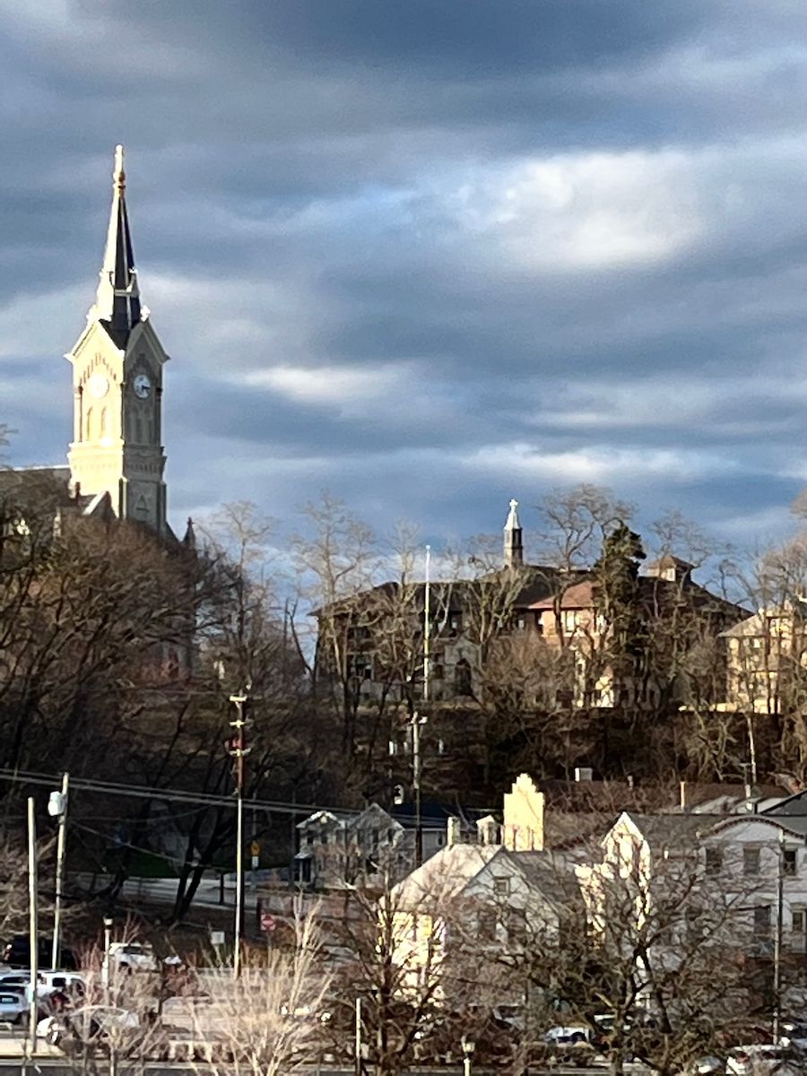 Una iglesia con una torre del reloj, rodeada de edificios residenciales y árboles sin hojas.