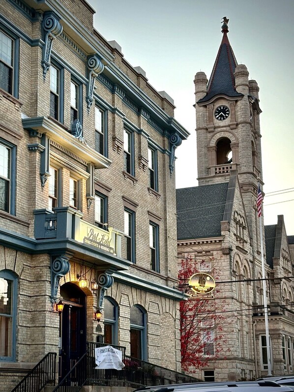 A historic building with a clock tower, a sign for 'Port Hotel' indicating lodging and events, and a banner for 'BART'S DINER'. - The Port Hotel (Port Washington)