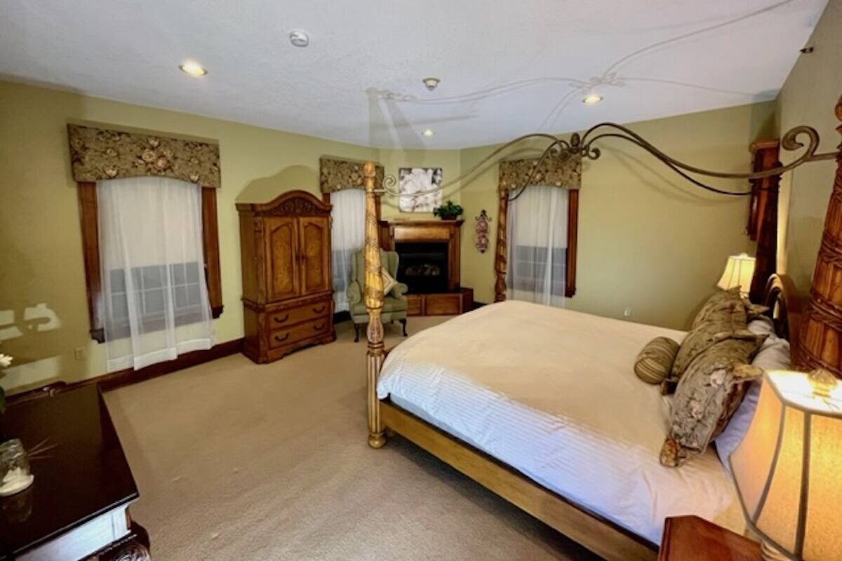 A bedroom with a four-poster bed, a wooden wardrobe, and a fireplace.