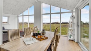 Un'ampia stanza con ampie finestre, un tavolo in legno con generi per la colazione e vista sulla campagna.