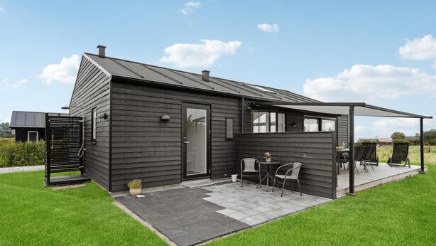 Une maison moderne dotée d’un patio couvert, d’une porte et d’un petit jardin.