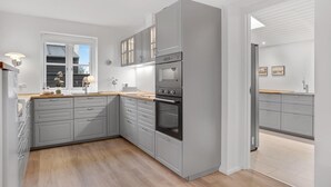 A modern kitchen with grey cabinets, a built-in oven, and a window with a view.