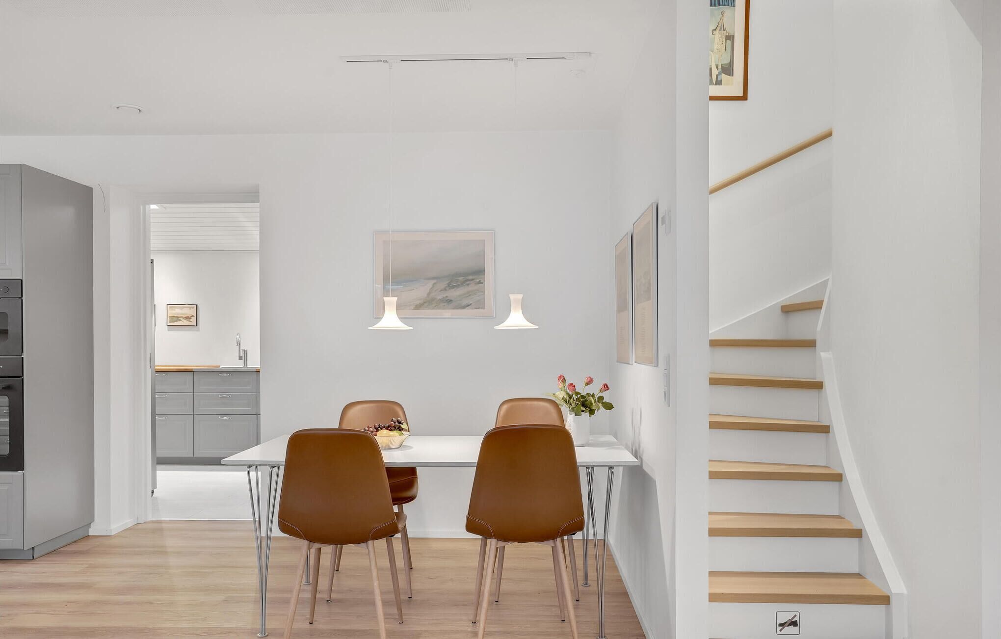 Een moderne keuken met een eetgedeelte, een houten trap en een uitzicht op de aangrenzende woonruimte.