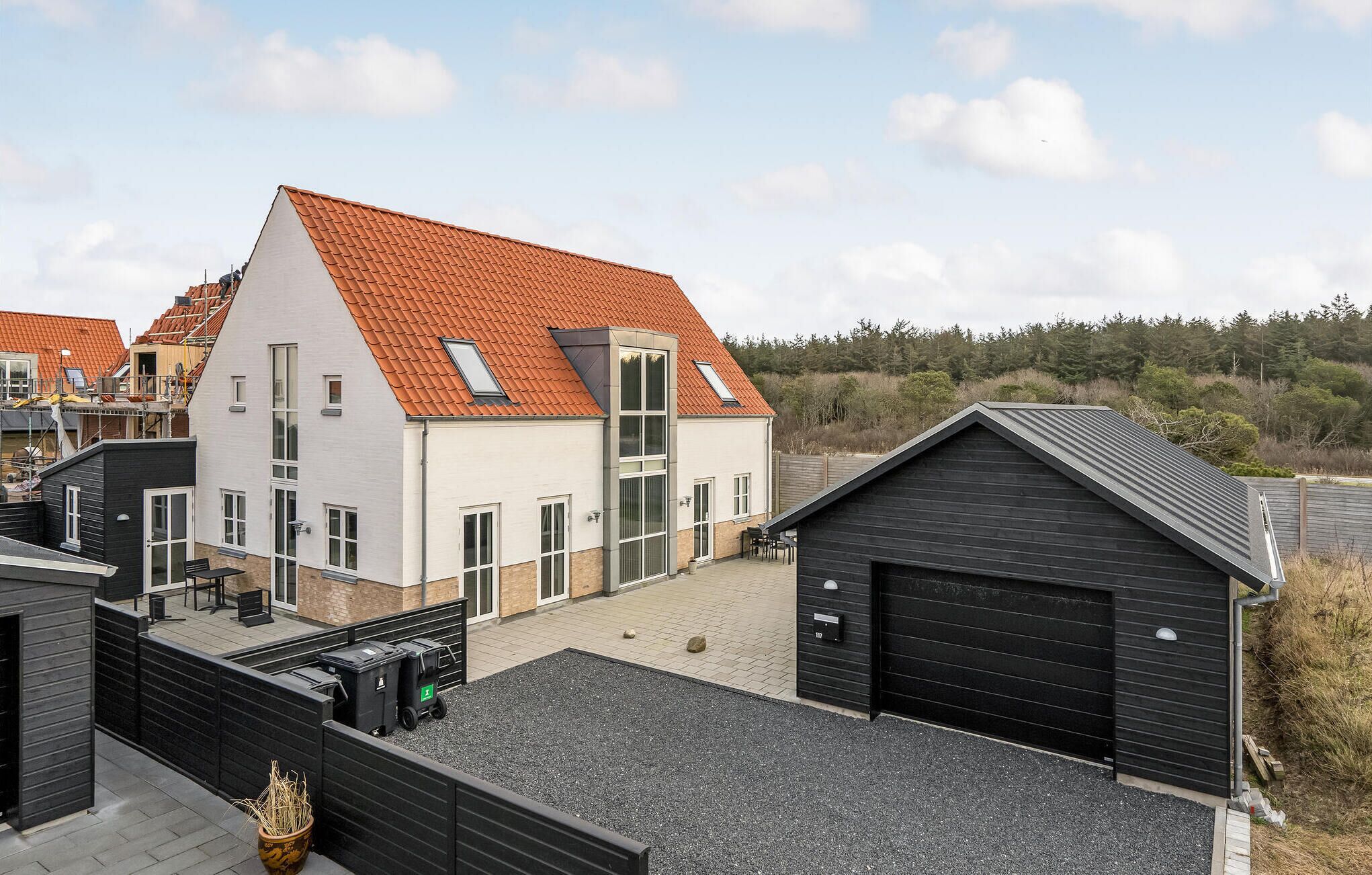 Et moderne hus med to etager, skråtag, store vinduer og en garage.