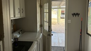 Uma lavanderia com máquina de lavar, secadora e porta para o exterior.