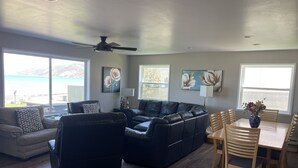A spacious living room with a large sectional sofa, a dining table with chairs, and artwork on the walls. - Lakefront 7 bed/3 bath home in Beautiful Bear Lake (Laketown)
