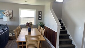 A dining area with a wooden table and chairs, a vase with flowers, a window, and a staircase. - Lakefront 7 bed/3 bath home in Beautiful Bear Lake (Laketown)