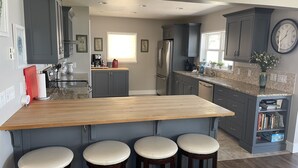 A modern kitchen with a wooden island, bar stools, and a clock on the wall. - Lakefront 7 bed/3 bath home in Beautiful Bear Lake (Laketown)