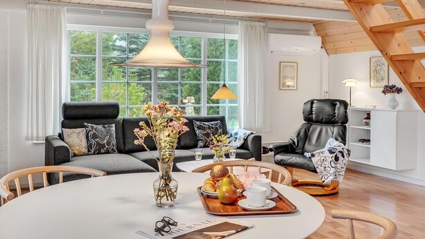 A modern living room with a sofa, a dining table with a vase of flowers, and a chair.