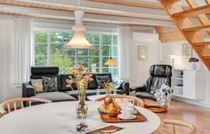 A modern living room with a sofa, a dining table with a vase of flowers, and a chair. - 2 bedroom gorgeous home in Tarm (Tarm)