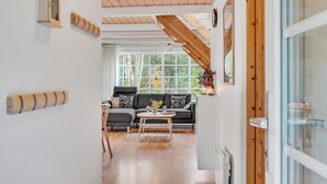 A modern interior with a wooden ceiling, a sofa, a coffee table, and a window with a view of trees.