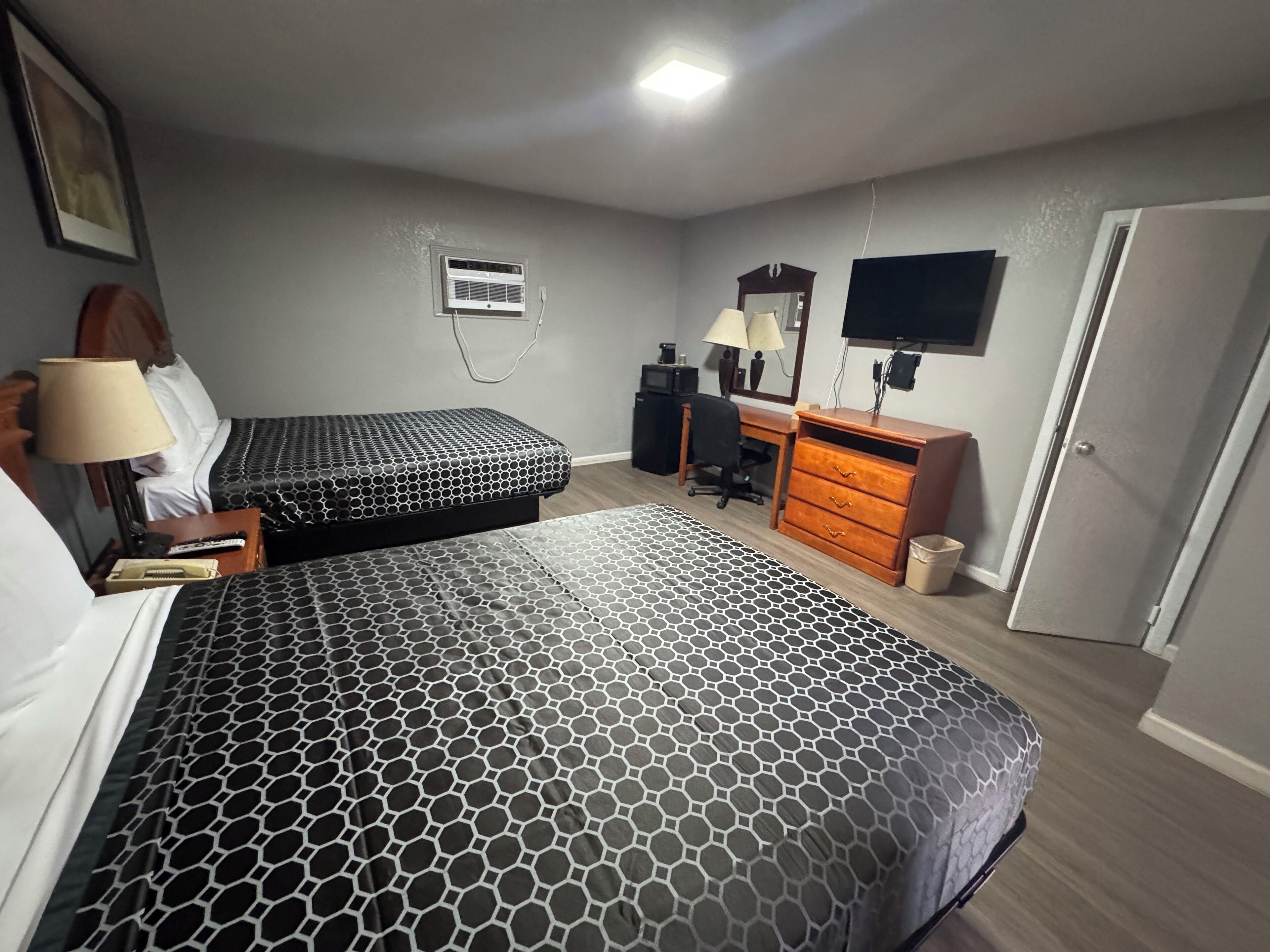 A hotel room with two beds, a desk, a chair, a television, and a wardrobe.