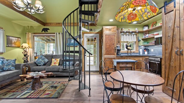 A rustic interior with a spiral staircase, a dining area, and a kitchen with wooden cabinets. - Jim Thorpe Rustic Cabin With Hot Tub, EV Charger, BBQ Grill & Outdoor Games! (Jim Thorpe)