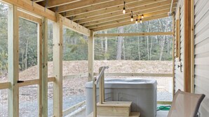 A wooden deck with a hot tub, steps, and a metal chair. - Jim Thorpe Rustic Cabin With Hot Tub, EV Charger, BBQ Grill & Outdoor Games! (Jim Thorpe)